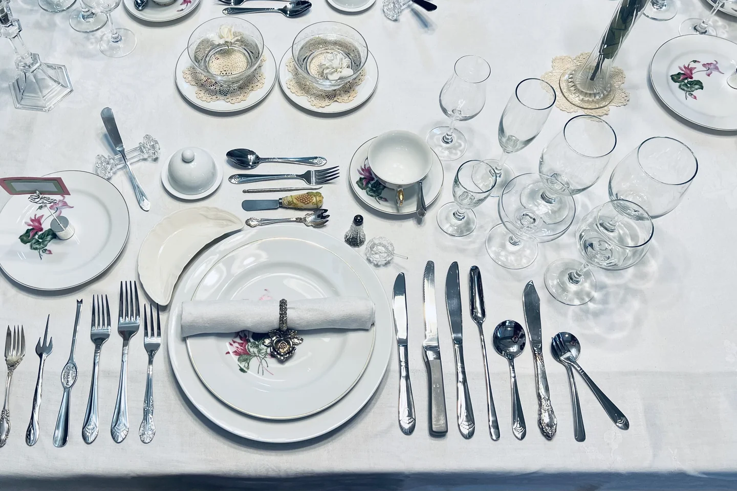 Vue de dessus d'un couvert complet : assiettes, verres, tasses et nombreux couverts